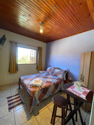 a bedroom with a bed and a table and a window at Aconchego do céu in Conceição da Ibitipoca