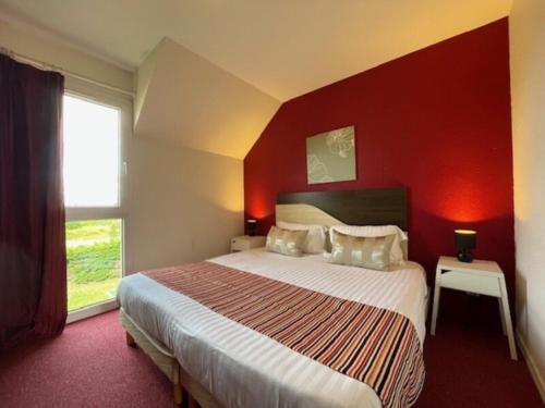 a bedroom with a large bed with a red wall at Eurocéan Adonis Budget in Guérande