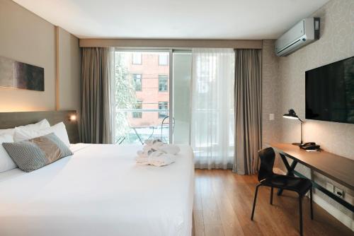 a hotel room with a bed and a desk and a window at CasaSur Bellini in Buenos Aires