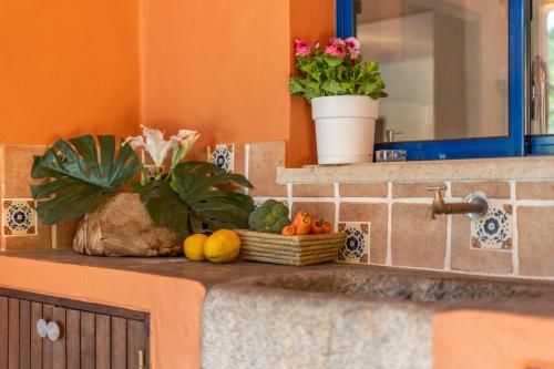 a counter with a bowl of fruit and a basket of flowers at Villa Bambu in Charneca