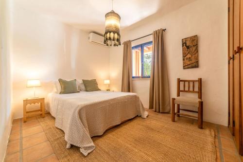 a bedroom with a bed and a chair and a window at Villa Bambu in Charneca