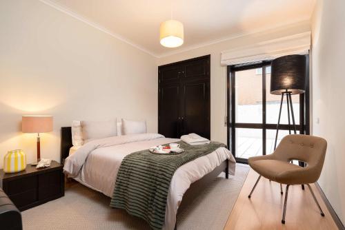 a bedroom with a bed and a chair and a window at Oceanfront Views & Modern Elegance by HostWise in Vila do Conde