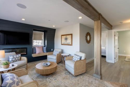 a living room with a couch and chairs and a tv at The Newport Lofts - 617 Thames Street in Newport