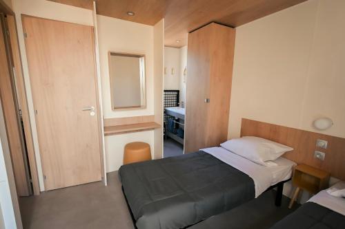 a small bedroom with a bed and a mirror at Camping Lou Broustaricq in Sanguinet