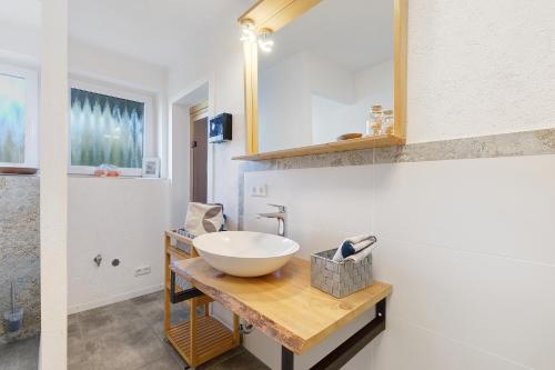 a bathroom with a white bowl sink on a wooden counter at Ferienwohnung glüxnest in Bernstadt