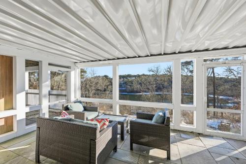 a screened in porch with chairs and tables and windows at Lake front, Near Beach, AC, WiFi, Pet Friendly near Bike Path in Chatham