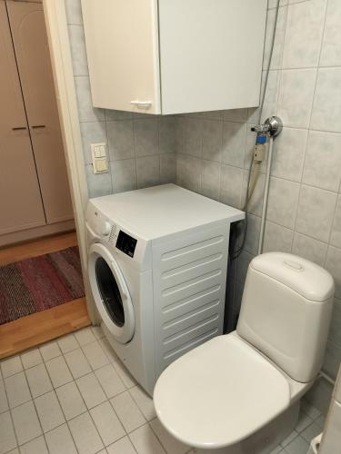 a washing machine and a toilet in a bathroom at Varakoti Helmi in Loimaa