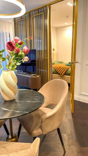 a room with a table and a vase with roses at Vilnius Luxurious flat in Vilnius