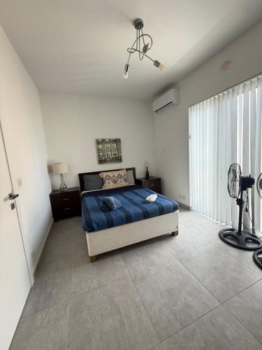 a bedroom with a bed with a blue comforter and a fan at Azure Dome Residences in Għajnsielem