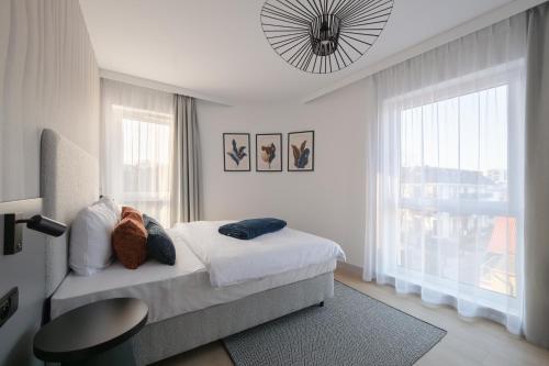 a white bedroom with a bed and a large window at Baltic Waves Resort by PI Apartments - Official Operator in Międzyzdroje