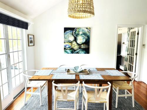 a dining room table with chairs and a painting on the wall at Beach Glass—Space, Fun Furry Friends Welcome in Brewster