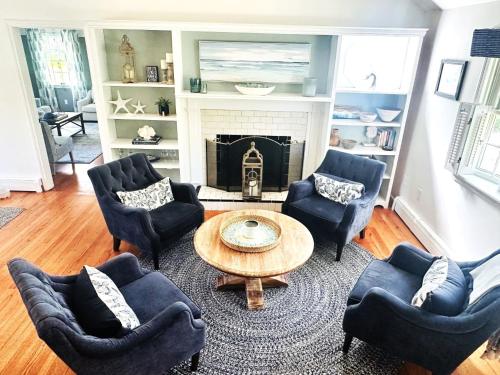a living room with chairs and a table and a fireplace at Beach Glass—Space, Fun Furry Friends Welcome in Brewster