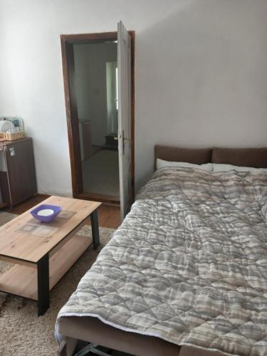 a bedroom with a bed and a wooden table at Apartman Cicović in Foča