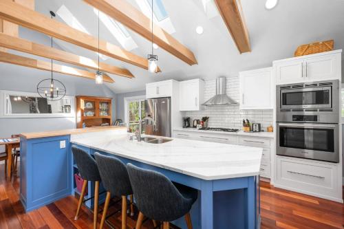 a kitchen with white cabinets and a blue island with bar stools at Gorgeous Cape Cod Retreat Near Town Neck in East Sandwich