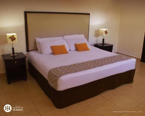 a bedroom with a large bed with two lamps at Hotel Hacienda de Izamal in Izamal