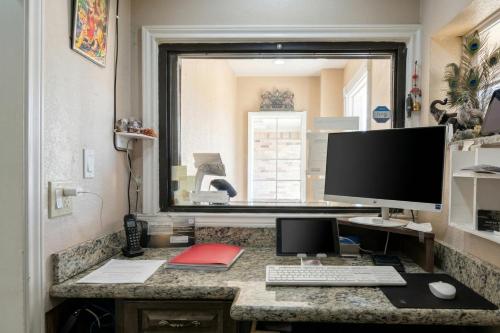 a computer desk with a monitor and a keyboard and mouse at Golden Motel Near Houston Medical Center in Houston