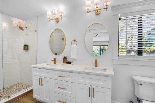 a white bathroom with a sink and two mirrors at The Retreat at Anna Maria Island Inn in Bradenton Beach