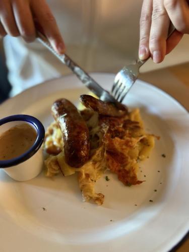 a plate of food with sausage and a cup of sauce at Auberge du Mas de la Barque in Villefort