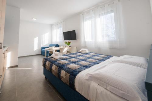 a white bedroom with a large bed and a table at FEEL - Palazzo Ortelli in Bergamo