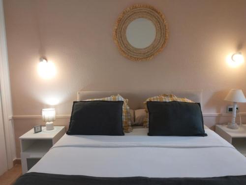 a bedroom with a white bed with two tables and a mirror at Apartamento Verdemare in Corralejo