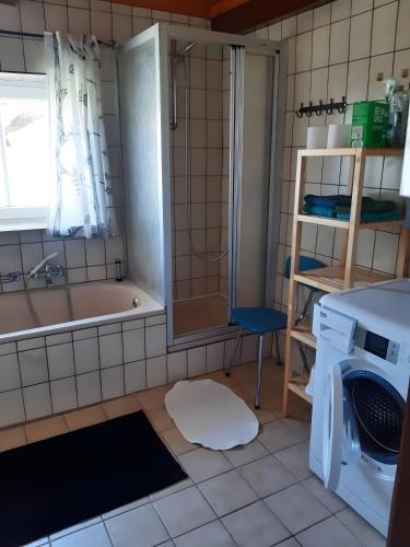 a bathroom with a tub and a washing machine at Ferienhaus Petersen in Langeneß