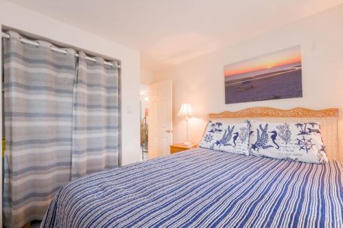 a bedroom with a bed with a blue and white comforter at Sand, Sun Serenity: Cape Cod Escape in East Sandwich