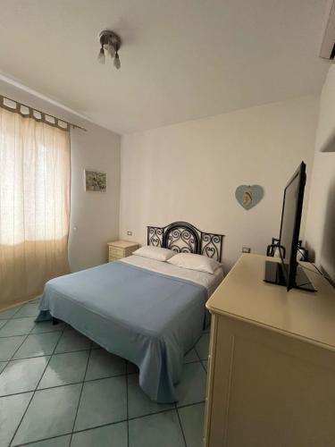a bedroom with a bed and a desk with a television at La Casetta in Lacco Ameno