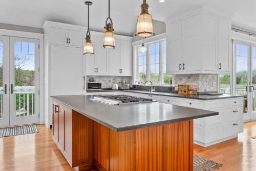 a kitchen with white cabinets and a large island at Marshside Cape Escape with Space Views in Sandwich