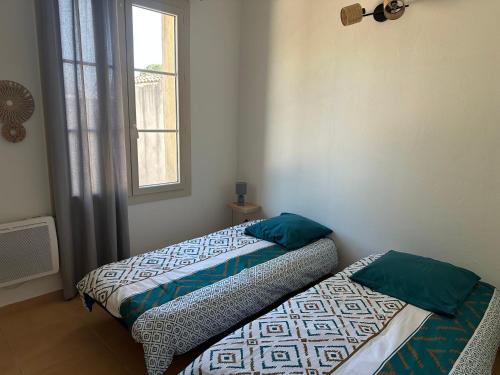 two twin beds in a room with a window at Gîte Les 2 oliviers in Canet