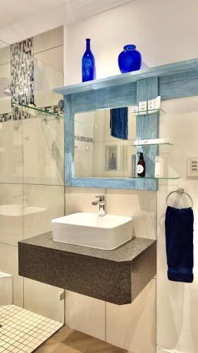 a bathroom with a sink and a blue shelf at Somerset View Guest House in Somerset West