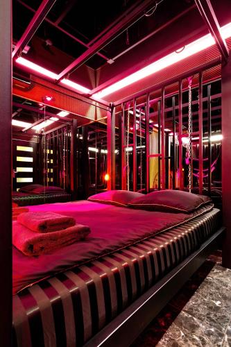 a bedroom with a large bed with pink lighting at BDSM room Bydgoszcz z jacuzzi dużym tarasem i Balią zewnętrzną in Bydgoszcz
