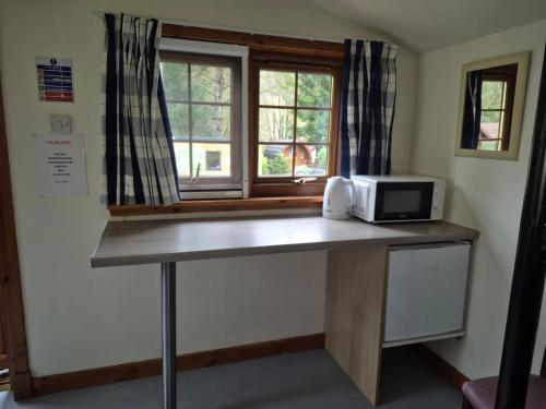 a kitchen with a counter with a microwave and a window at By The Way Campsite, Trekker, Nevis in Tyndrum
