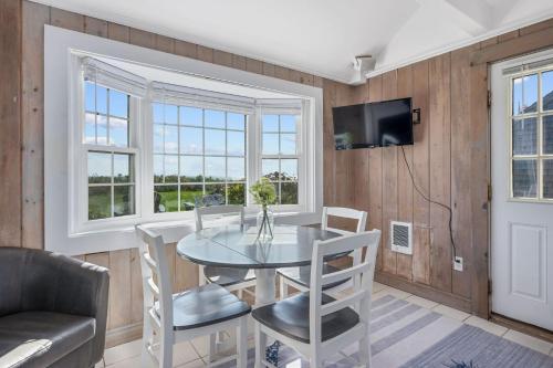 a dining room with a glass table and chairs at The Shell Cottage - Where Beach Dreams Begin in South Yarmouth