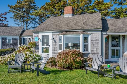 a house with two chairs and a table in the yard at Lost at Seaside – Your Cozy Coastal Hideaway in South Yarmouth