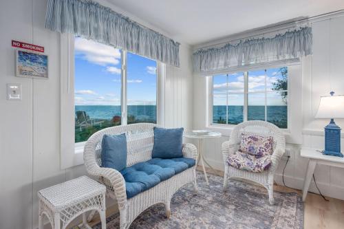 a living room with two chairs and a table and windows at Oceans Edge: Drift, Dream, Repeat in South Yarmouth