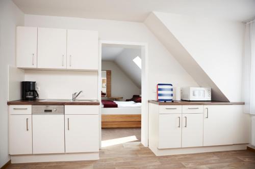 a kitchen with white cabinets and a room with a bed at Schlicks Dümmer Kojen in Lembruch
