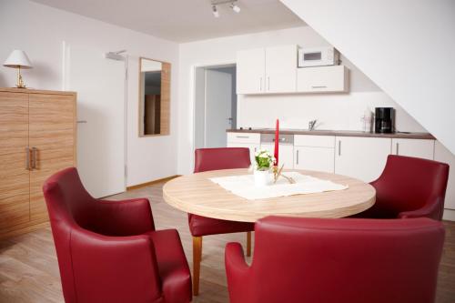a kitchen and dining room with a wooden table and red chairs at Schlicks Dümmer Kojen in Lembruch