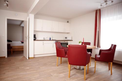 a kitchen and dining room with red chairs and a table at Schlicks Dümmer Kojen in Lembruch