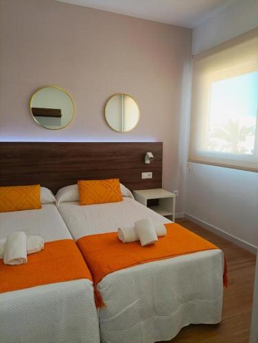 two beds in a bedroom with two mirrors on the wall at Iberflat Apartamentos Marynton in Benicarló