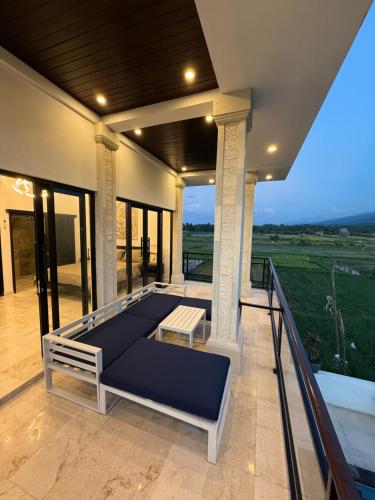 a porch with a bed and a balcony with a view at Murni’s House in Lovina