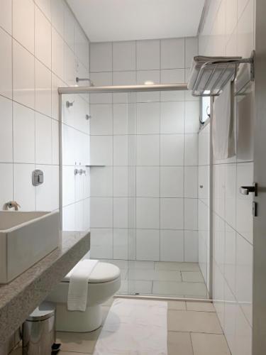 a white bathroom with a toilet and a sink at Oásis Hotel in Araguaína