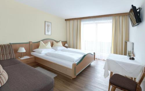 a bedroom with a bed and a couch and a window at Gästehaus Luise in Waidring