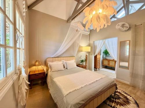 a bedroom with a large bed and a chandelier at Villa Chic à Petit-Havre in Le Gosier
