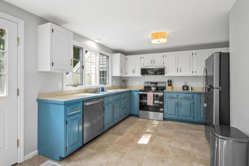 a kitchen with blue cabinets and a black refrigerator at On Cape Time – Family Friendly Relaxing Escape in Osterville