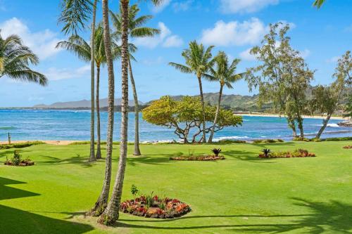 a view of a golf course with palm trees and the ocean at NEW Beachfront 2 Bedroom Ocean View Oasis and Pool in Kapaa