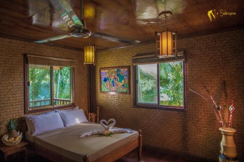 una camera da letto con un letto in una stanza con finestre di La Salangane Caalan Beach Villa a El Nido