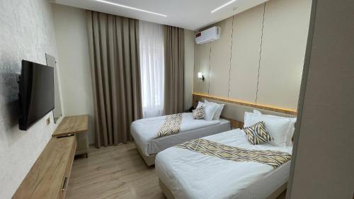 a hotel room with two beds and a flat screen tv at Sahro Hotel Khiva in Khiva