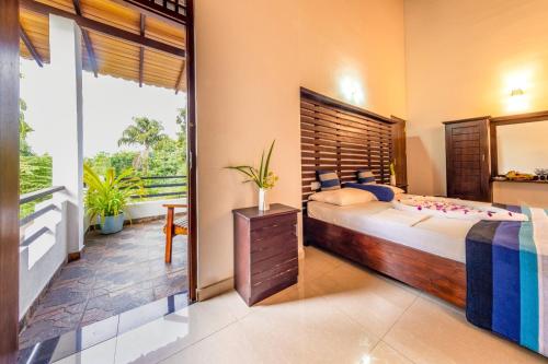 a bedroom with a large bed and a balcony at Owinmo Hotel & reception Hall in Galle