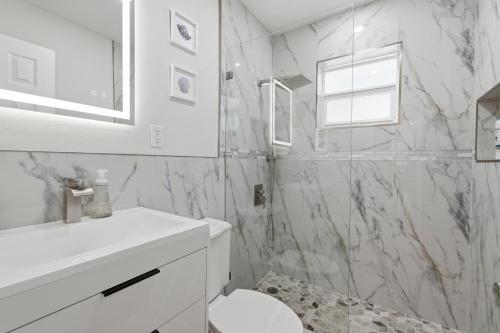a white bathroom with a toilet and a sink at Naples Triplex Retreat in Naples
