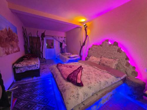 a room with two beds with purple lights at Résidence Arinas in Al Barāwikah
